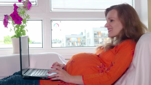 Donna incinta sorridente con computer portatile e carta di credito che acquista beni nel negozio online — Video Stock