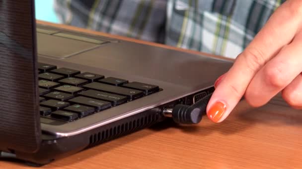 Vrouwelijke hand sluit het netsnoer aan op een laptopcomputer — Stockvideo