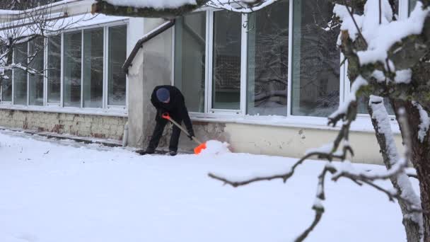 Man ren cnow med spade nära husvägg med stora fönster. 4k — Stockvideo