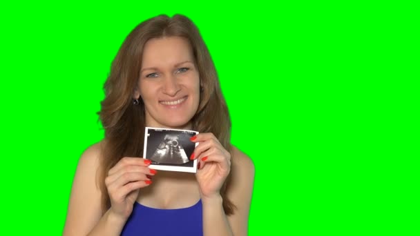 Jeune femme femme montrant sa photo d'échographie du ventre et regardant dans la caméra — Video