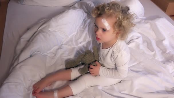 Ребенок с клейкой повязкой на голове и ноге — стоковое видео