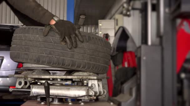 Macho trabajador montaje neumático en llanta de rueda utilizando máquina especial . — Vídeos de Stock