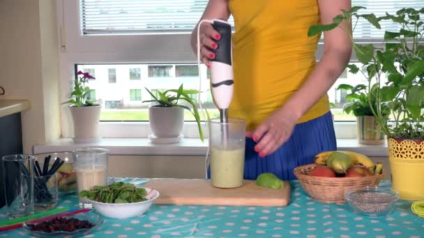 A barriga de mãe expectante e as mãos misturam leite e coquetel de frutas orgânicas com misturador — Vídeo de Stock