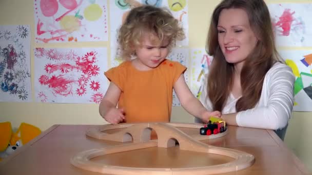 Menina bonito com mãe bonita empurrando brinquedo trem locomotiva na ferrovia — Vídeo de Stock