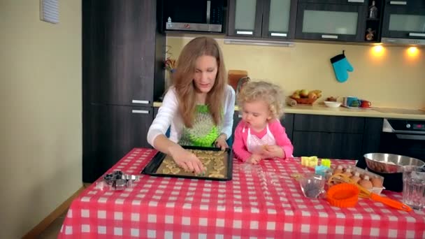 Linda niña ayudante con hermosas galletas lugar madre en la lata del horno — Vídeos de Stock