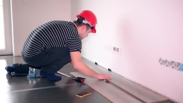Genç bir işçi adam laminat zemin panelleri döşeme. — Stok video