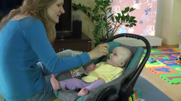 Joven madre cuchara alimentar a su bebé niña. 4K — Vídeo de stock