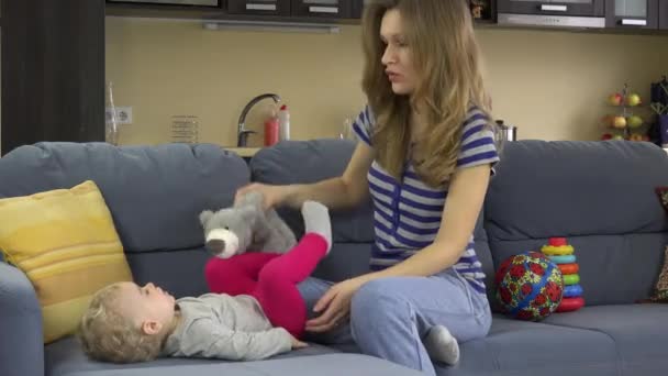 Ung glad mamma spela med flicka på soffa med leksak. 4k — Stockvideo