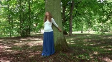 Yalın Park büyük ağaç gövdesi üzerinde duran rahat hamile kadın