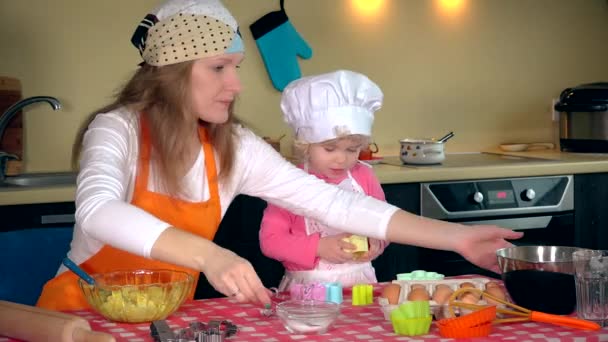 Niedliches kleines Mädchen und schöne Mutter in Schürzen spielen beim Kneten von Teig — Stockvideo