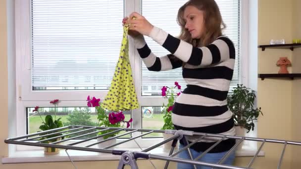 Těhotná žena pověsit prádlo doma — Stock video