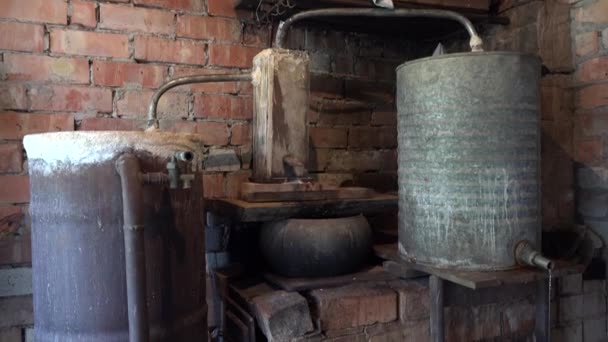農村の台所で強いウォッカ アルコールを取得する国内の古い銅ボイラーの下に傾けます Uhd ビデオ クリップ — ストック動画