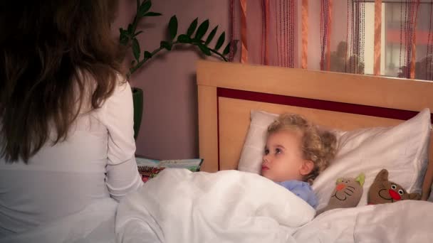Toddler girl child in bed with toy cats and listening to mother reading book — Stock Video