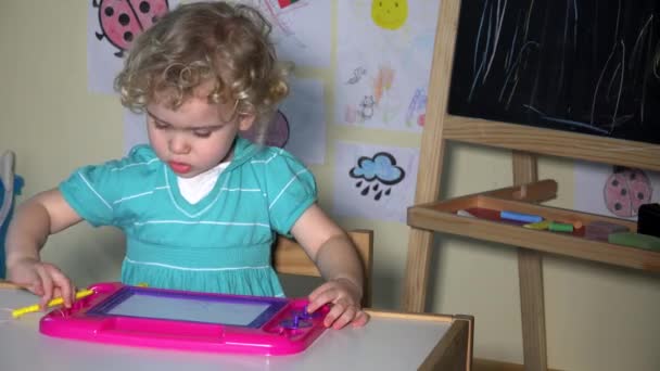 Kreatives Mädchen Kind Zeichnung o Magnettafel am Tisch sitzend — Stockvideo