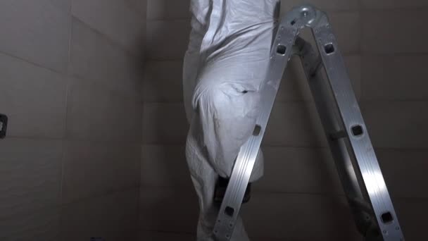 Bauarbeiter steht auf Leiter und bohrt Löcher in Decke — Stockvideo