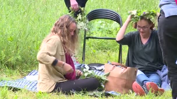 Madre e hija hacen corona de flores y plantas en el prado — Vídeos de Stock