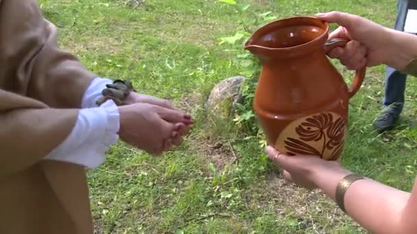 Kvinnlig prästinna tvätta händer och ansikte med heligt vatten från skogs källa — Stockvideo
