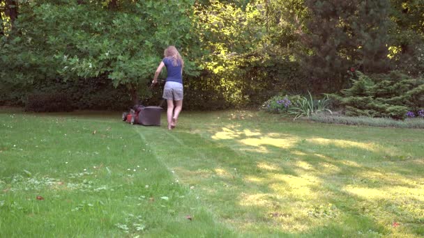 Femme pieds nus pré coupé avec tondeuse à gazon dans le jardin vert. 4K — Video