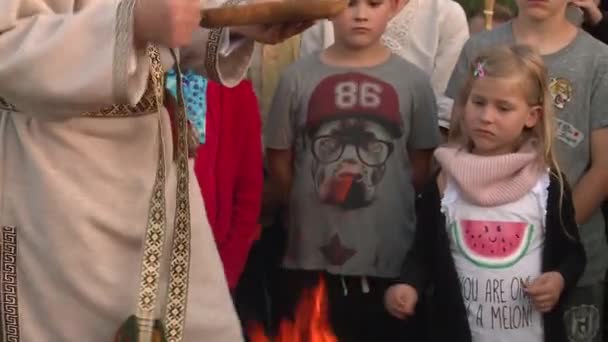 Senior priest man throw grain into fireplace flame surrounded by people — Stock Video