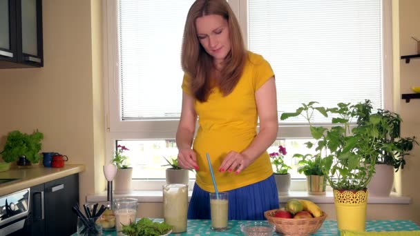 Schöne schwangere Frau trinkt frisches Obst und Milchcocktail und lächelt in die Kamera — Stockvideo