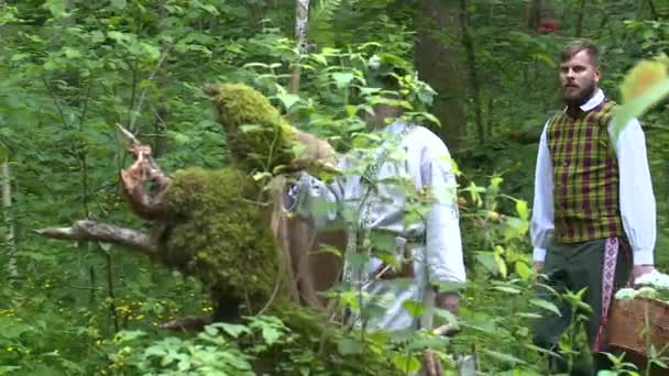 Люди в национальной одежде гуляют по лесу — стоковое видео