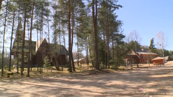 Деревянный дом бога церкви, видимый сквозь ветви деревьев, движущихся в ветре — стоковое видео