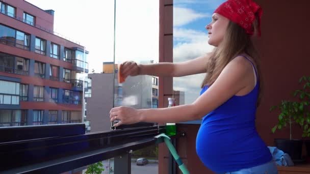Χαμογελαστή γυναίκα καθαρό παράθυρο στο σπίτι μπαλκόνι. Ευτυχισμένος κορίτσι έγκυος καθαρό γυαλί — Αρχείο Βίντεο