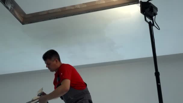 Travailleur avec spatule appliquer le remplissage sur le plafond de placoplâtre. Niche pour l'éclairage — Video