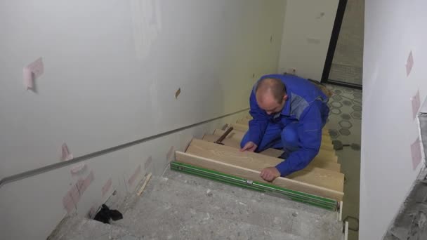 Kvalifikovaný pracovník s dřevěnou desku na schodech a na úrovni schodů — Stock video