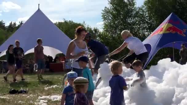 Children and adult people enjoy artificial foam in sports event. — Stock Video