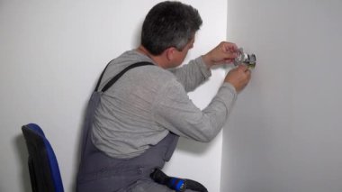 Tornavida ile elektrikçi adam kablolara elektrik soketi bağlayın