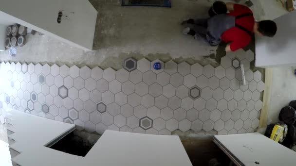 Hombre amateur colocando azulejos en forma de hexágono en el suelo del pasillo. Timelapse estático — Vídeos de Stock