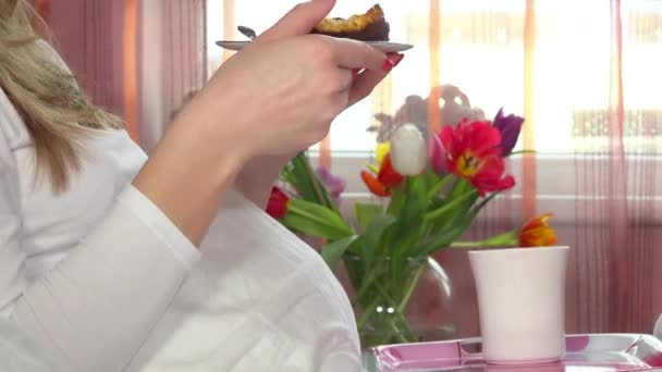 Vrouw geniet van het eten van zoete cake op helder venster en bloemen achtergrond — Stockvideo