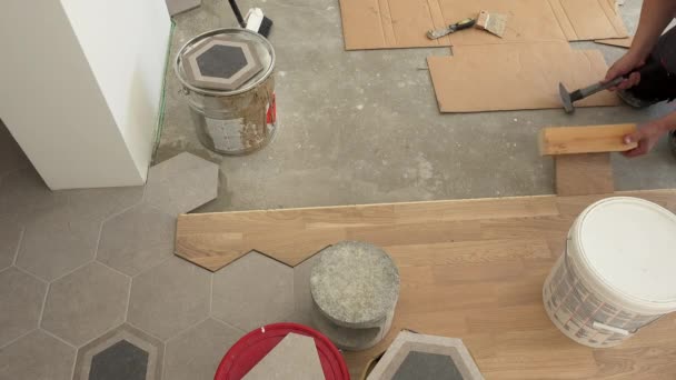 Skilled workers lay parquet floor boards. Man hitting board with hammer — Stock Video
