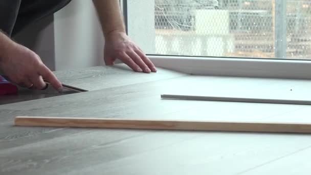 Разнорабочий укладывает деревянный пол в новом доме — стоковое видео