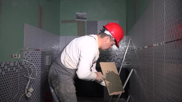 세라믹 타일을 설치하기 전에 타일에 시멘트 접착제를 추가하는 전문 타일러 — 비디오