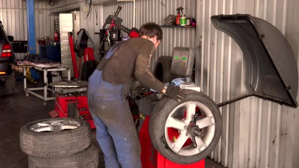 Mecánico que trabaja en la máquina de balance de ruedas — Vídeos de Stock