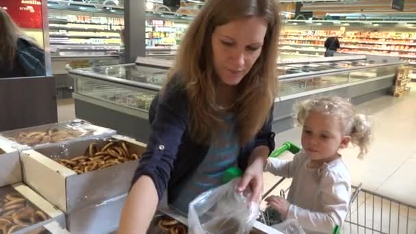 Zwangere moeder en peuter meisje pick bagel cookies in winkel markt — Stockvideo