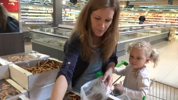 Pregnant mother and toddler girl pick bagel cookies in shopping market — Stock Video