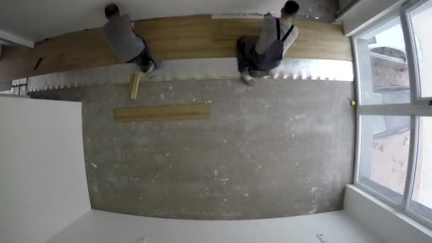 Män ansluter laminatskivor golvet i nya lägenhet rum — Stockvideo