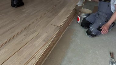 Adam beton üzerine parke zemin tahtası tutkal uygulamak için spatula kullanarak