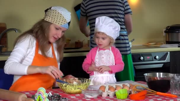 Loving parents with cute toddler girl with chef hat preparing cookies in kitchen — Stock Video