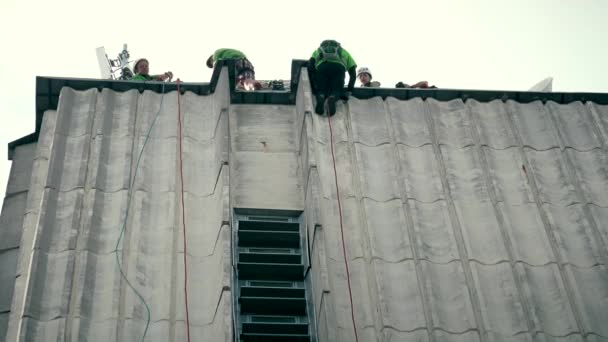 Fearless people descend down from high skyscraper and service staff care safety — Stock Video