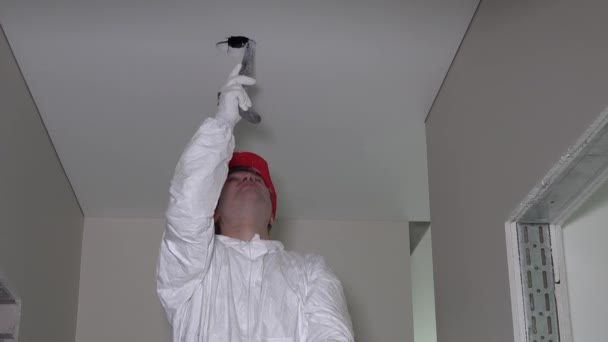 Electricien homme avec scie à main trou dans le plafond pour l'installation d'éclairage — Video