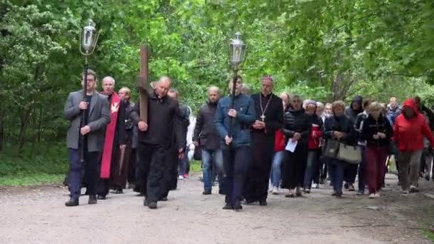 Kněz nosí dřevěný kříž přes štěrkovou cestu. Pojetí utrpení Ježíše Krista — Stock video