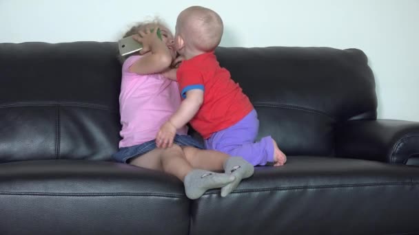 Irmã menina compartilhar smartphone com seu irmãozinho — Vídeo de Stock