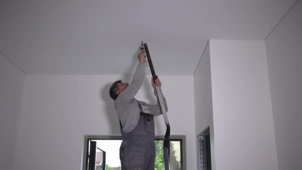 Worker man cut hole in plasterboard ceiling. Electrification works — 비디오