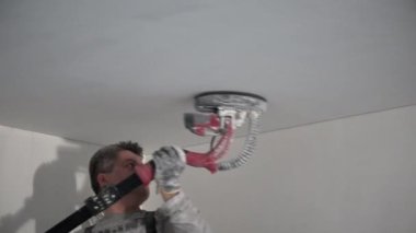 Erkek inşaat işçisi zımpara makinesi ile tavan yüzeyini yumuşatma