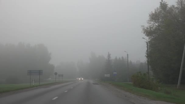 Автомобили едут по сельской асфальтовой дороге в тумане. 4K — стоковое видео