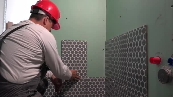 Accurate man with red helmet tiling wall with ceramic tiles — Stock Video